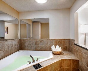 A bathroom with a freestanding bathtub, a mirror, and a basket of towels.