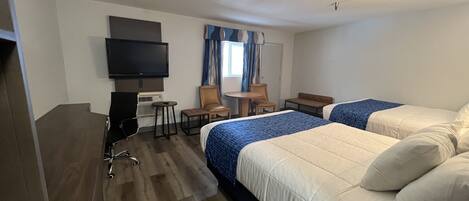 Habitación de hotel con dos camas, televisión, escritorio con silla y ventana con cortinas.