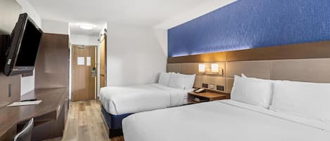 Een hotelkamer met twee bedden, een bureau, een televisie en een badkamers deur.