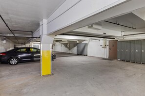 Un parking avec des planchers en béton, des casiers métalliques et une voiture garée près d’un pilier.