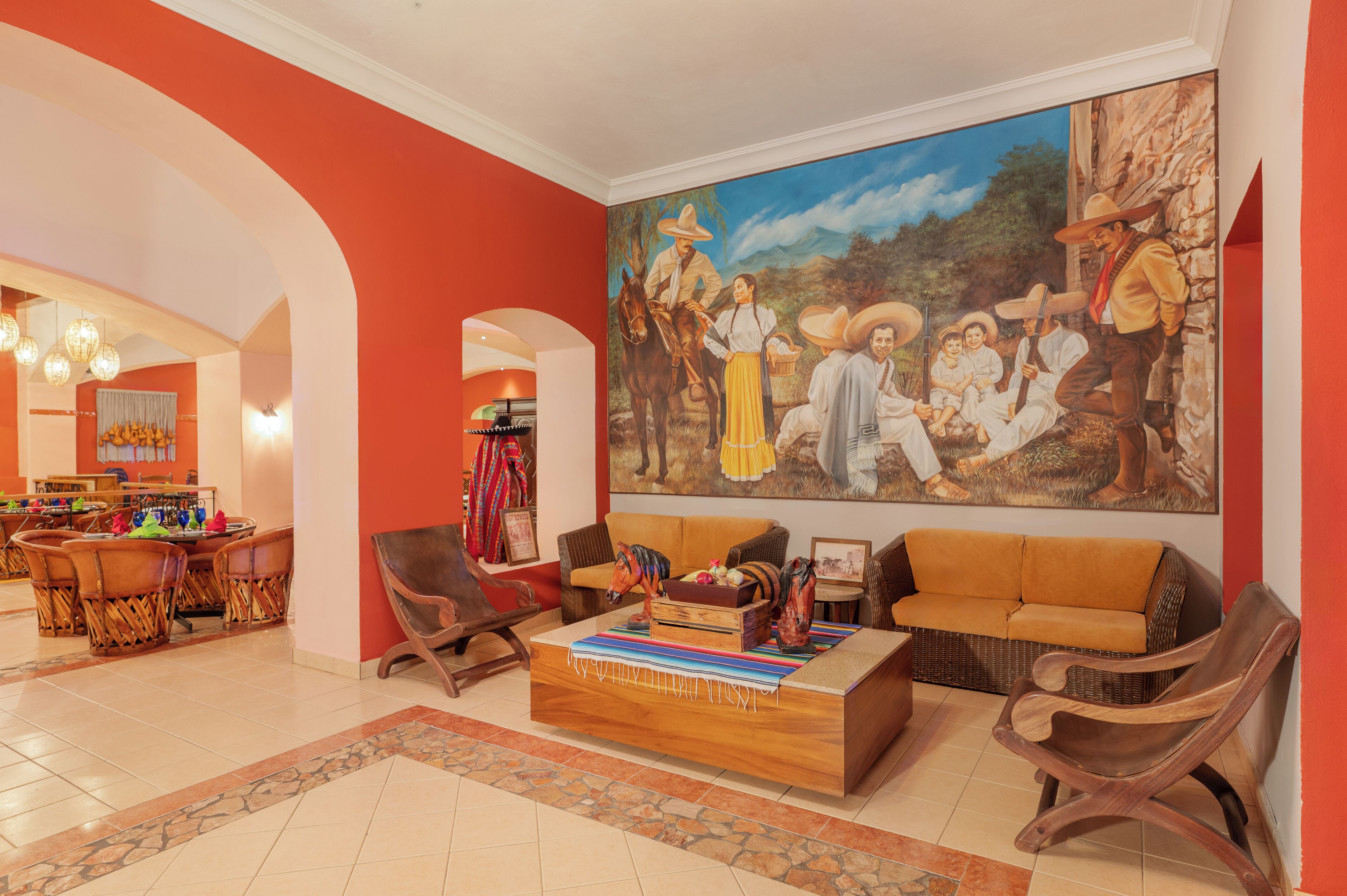 Eine geräumige Lobby mit einer großen Wandmalerei, einem Holztisch und einer Sitzecke mit Sofas und Sesseln.