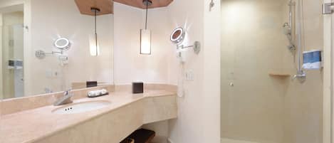 A bathroom with a large mirror, two sinks, a shower, and wooden ceiling beams.