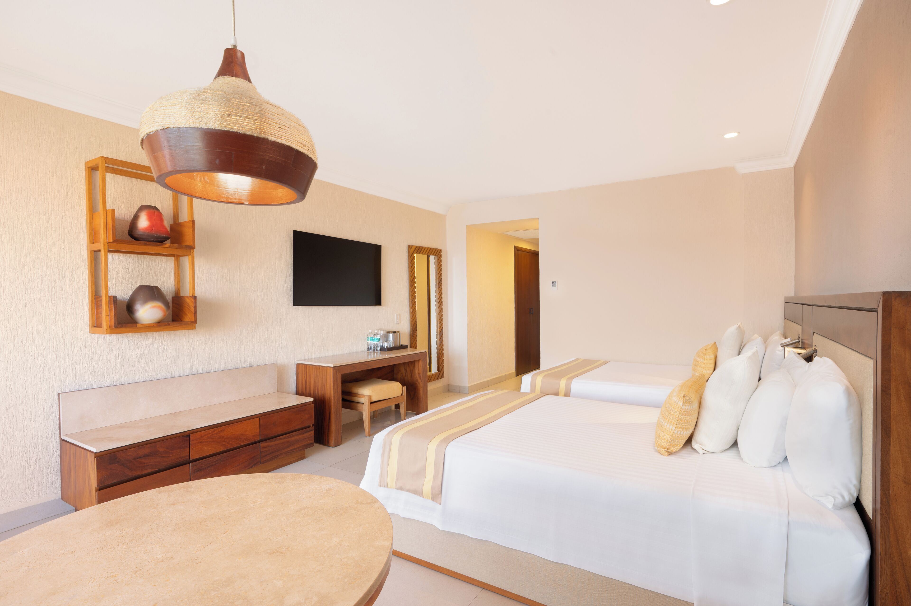 A hotel room with a bed, a desk, a chair, a television, and a hanging light fixture.