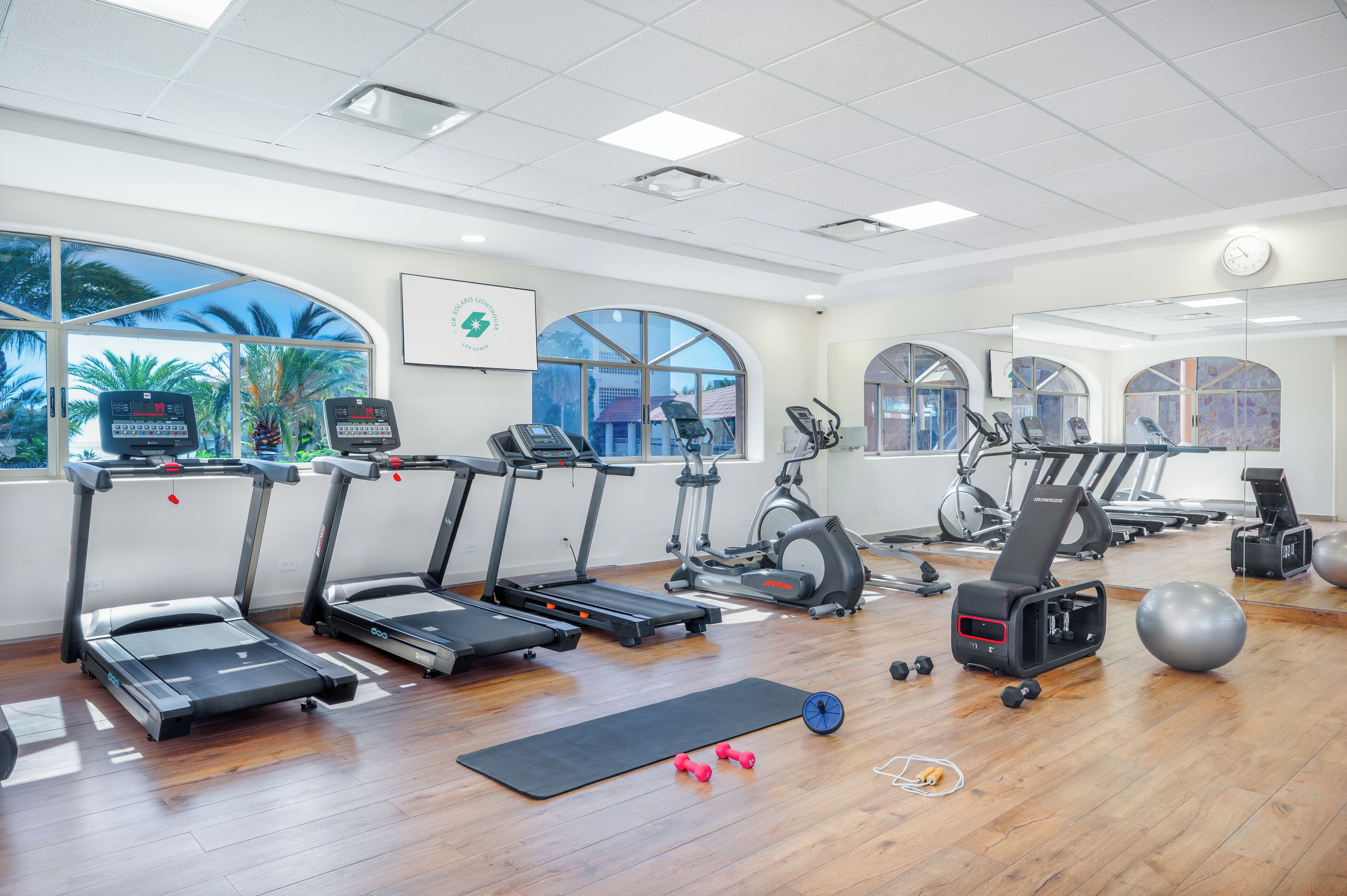 Un gimnasio con cintas de correr, elípticas y pelotas de ejercicio.