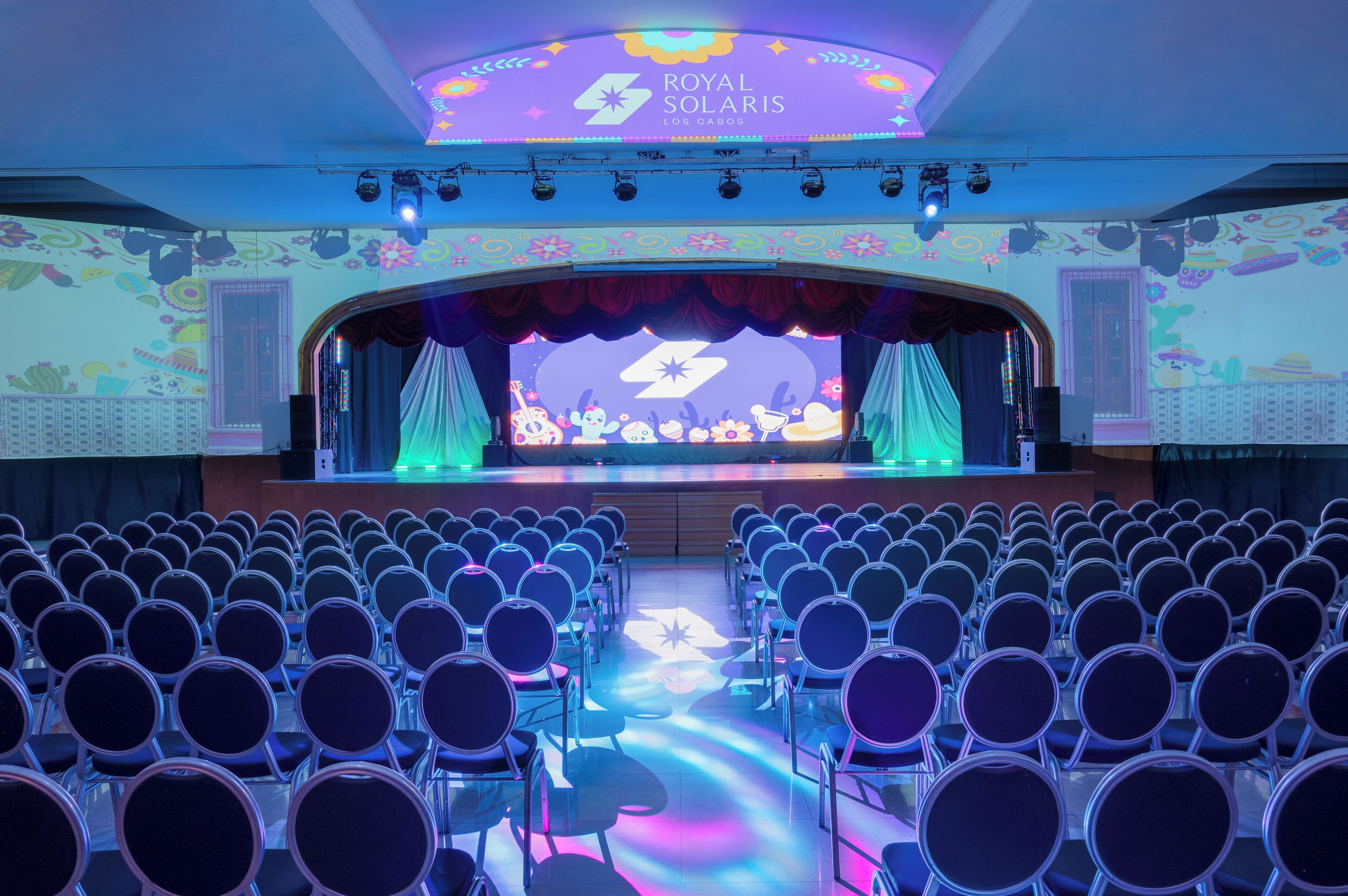 A theater with rows of chairs and a stage with a backdrop.