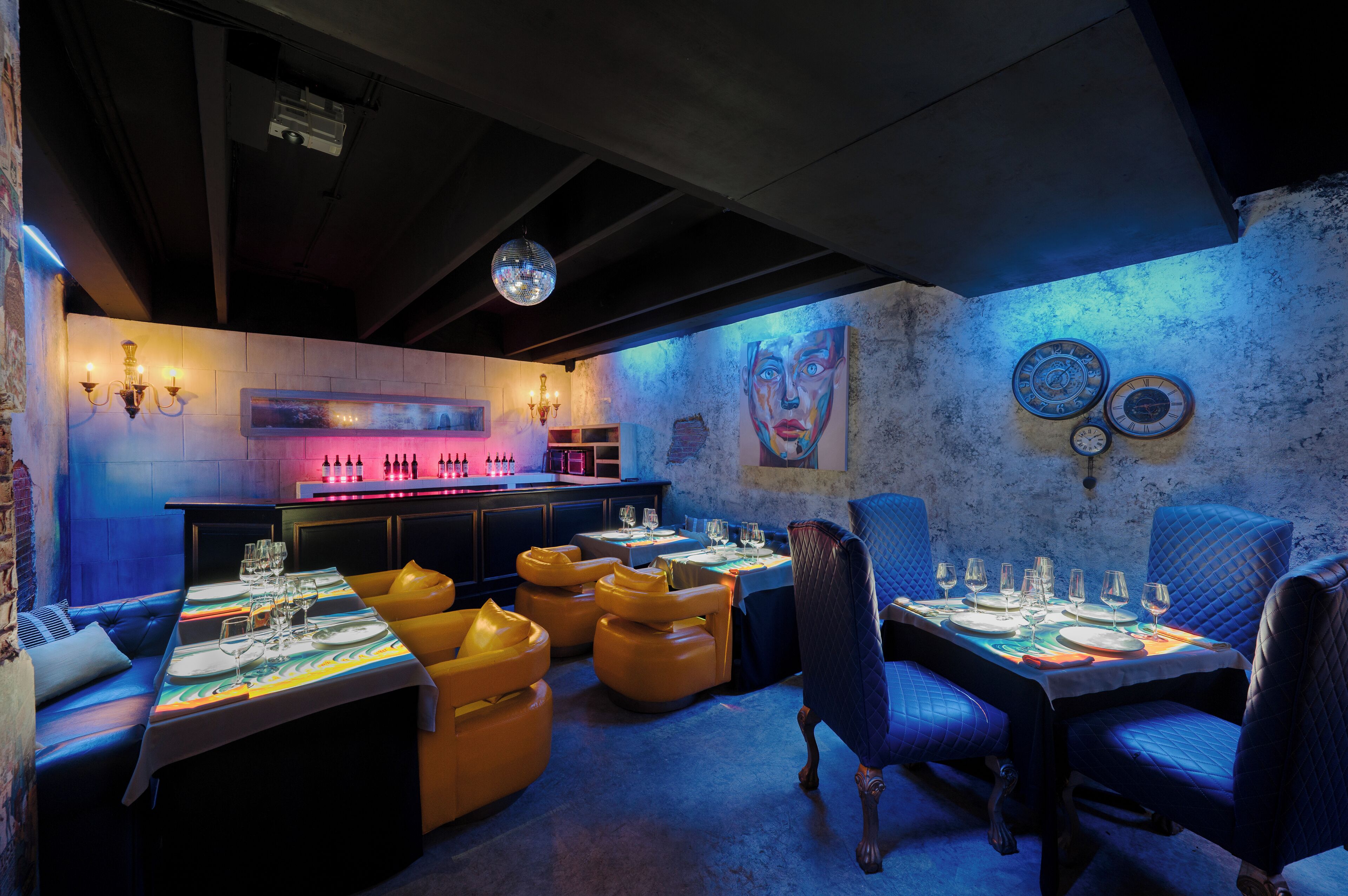 A restaurant with tables set for dining, cushioned seating, a bar area, and decorative wall art.