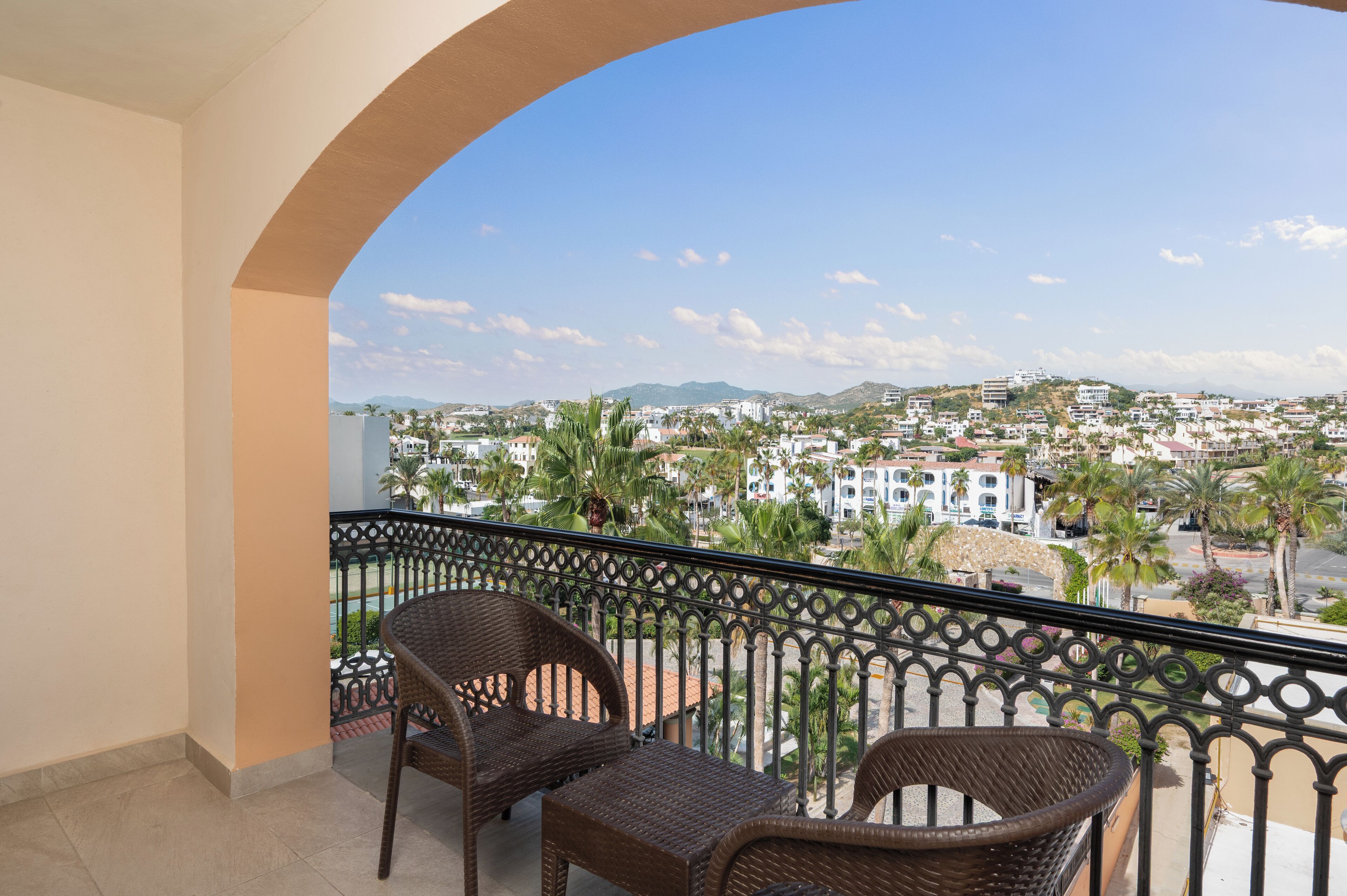A balcony with wicker furniture and a view of a coastal town.