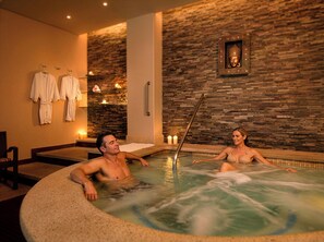 Um spa com banheira de hidromassagem, paredes de pedra e uma estátua de Buda.
