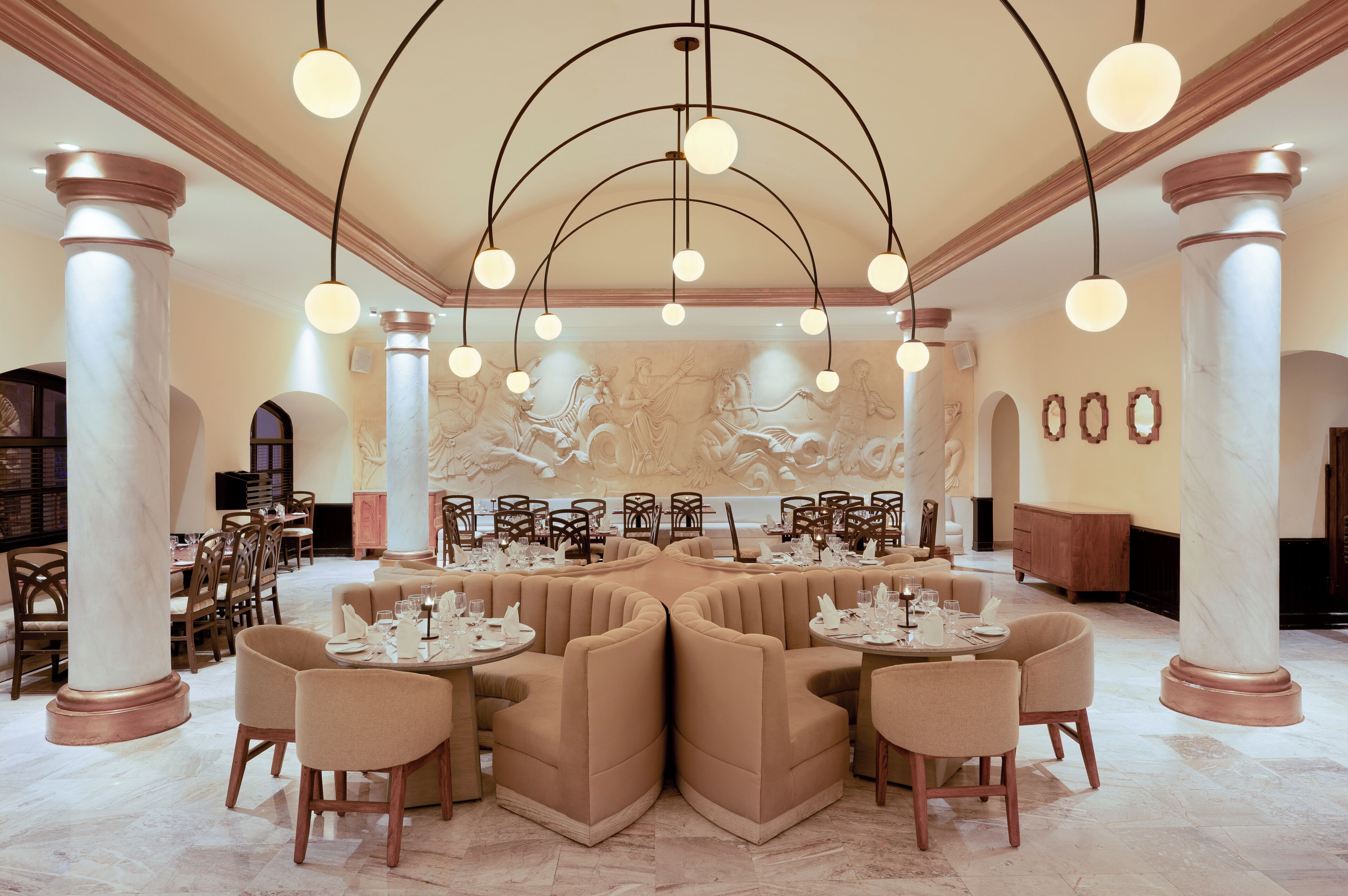 A spacious dining area with high ceilings, marble columns, and a central seating arrangement.