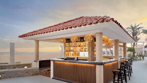 An outdoor bar with a tiled roof, a stone column base, and a wooden counter. - Royal Solaris Los Cabos & Spa - All Inclusive (San José del Cabo)