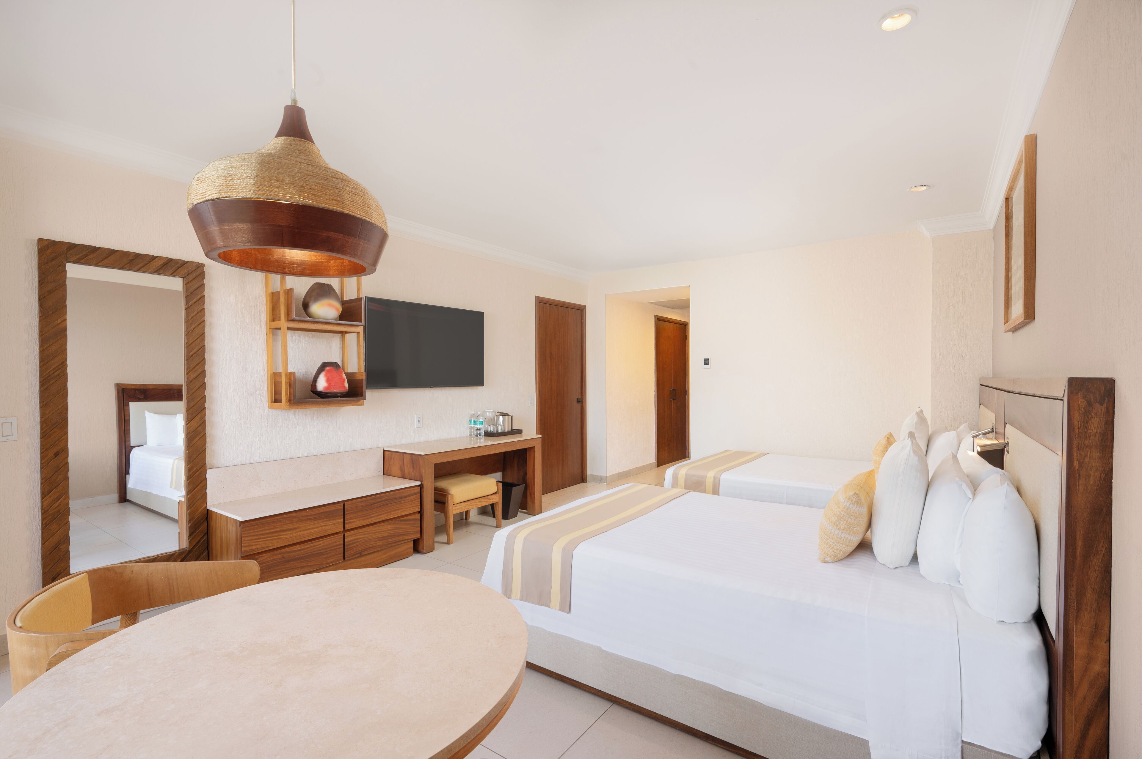 A hotel room with a bed, bedside table, chair, desk, and a television mounted on the wall.