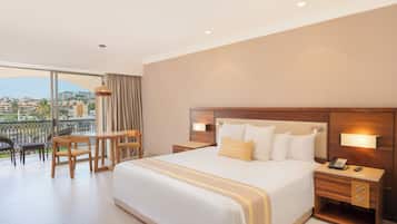 Habitación de hotel con una cama grande, un escritorio y una silla. Cuenta con un balcón y vistas a la ciudad.