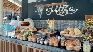 A pizza bar with various types of pizza, bread, and condiments displayed on wooden boards and shelves. - Royal Solaris Los Cabos & Spa - All Inclusive (San José del Cabo)