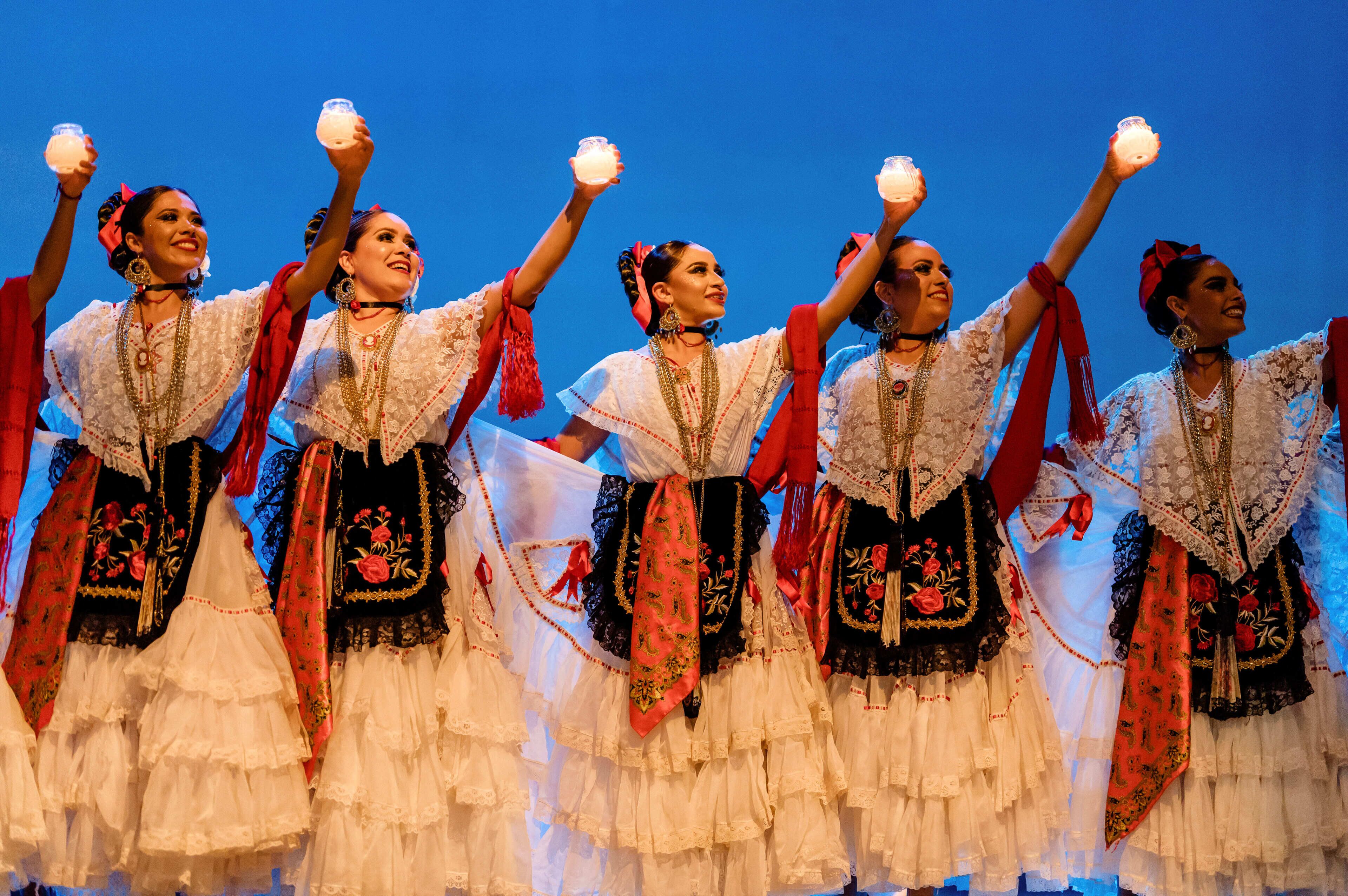 Un groupe de personnes, vêtues de costumes traditionnels, interprète une danse.