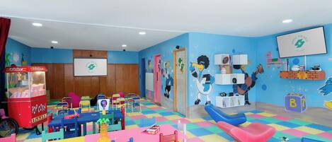 Une salle de jeux pour enfants avec des meubles aux couleurs vives, un chariot à pop-corn et des décorations murales ludiques.