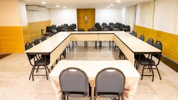 Une salle de conférence avec une longue table et des chaises, une porte en bois et un sol carrelé.