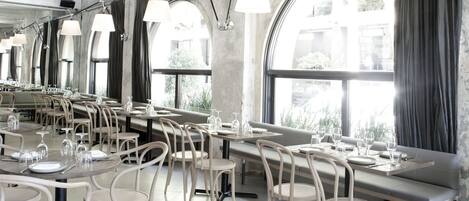Un restaurante con mesas largas, sillas y lámparas colgantes.
