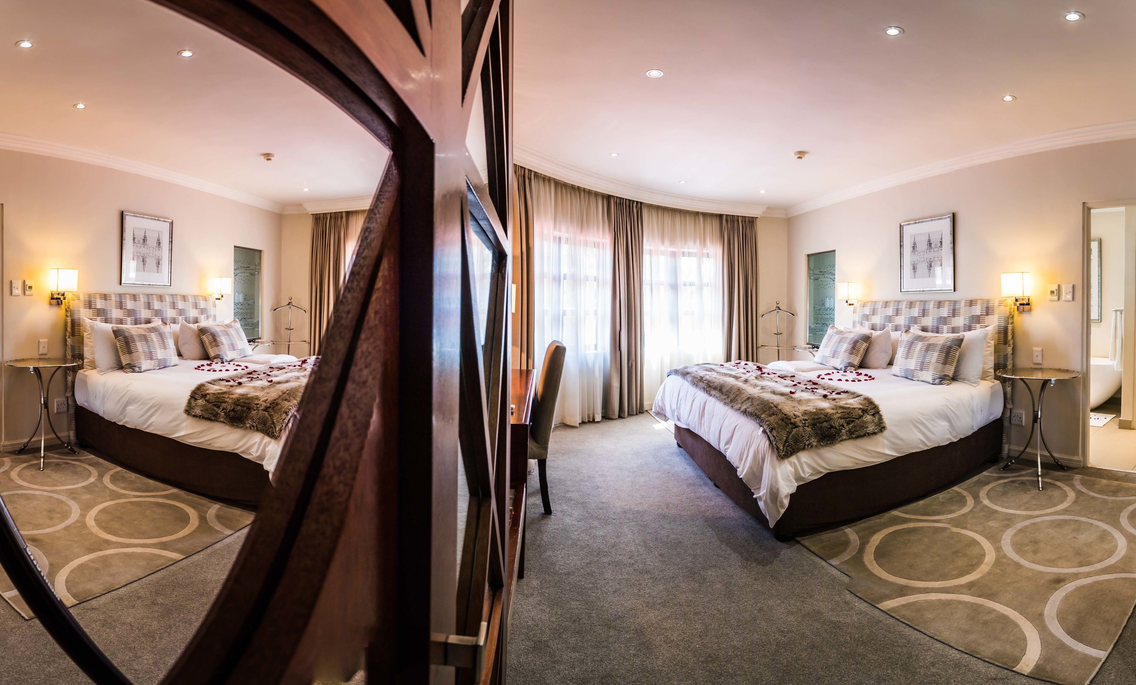 Een hotelkamer met twee bedden, een grote spiegel en uitzicht op de stad.