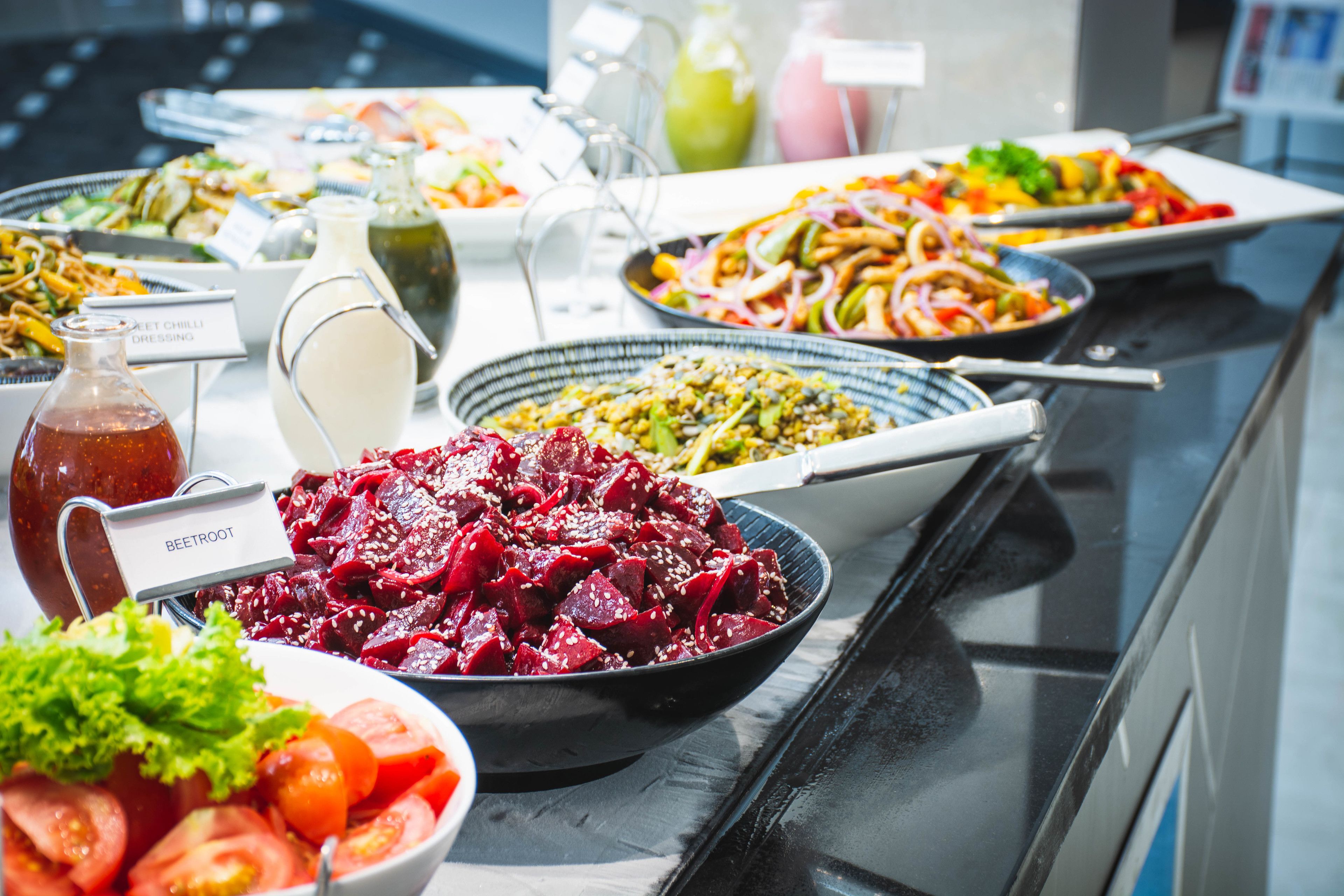 A buffet with various dishes including beetroot salad, a salad with tomatoes, and a dish with noodles.