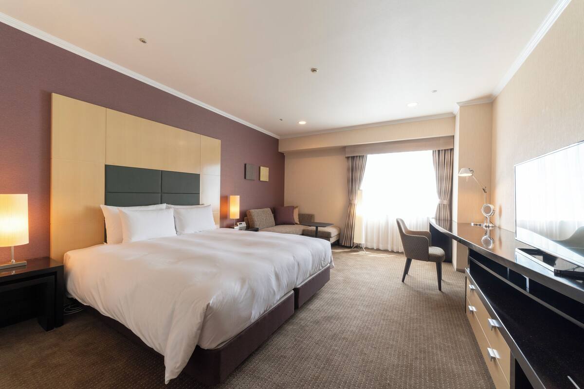 Een hotelkamer met een groot bed, een bureau, een stoel en een televisie.