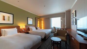 A hotel room with two beds, a desk, a chair, and a television.