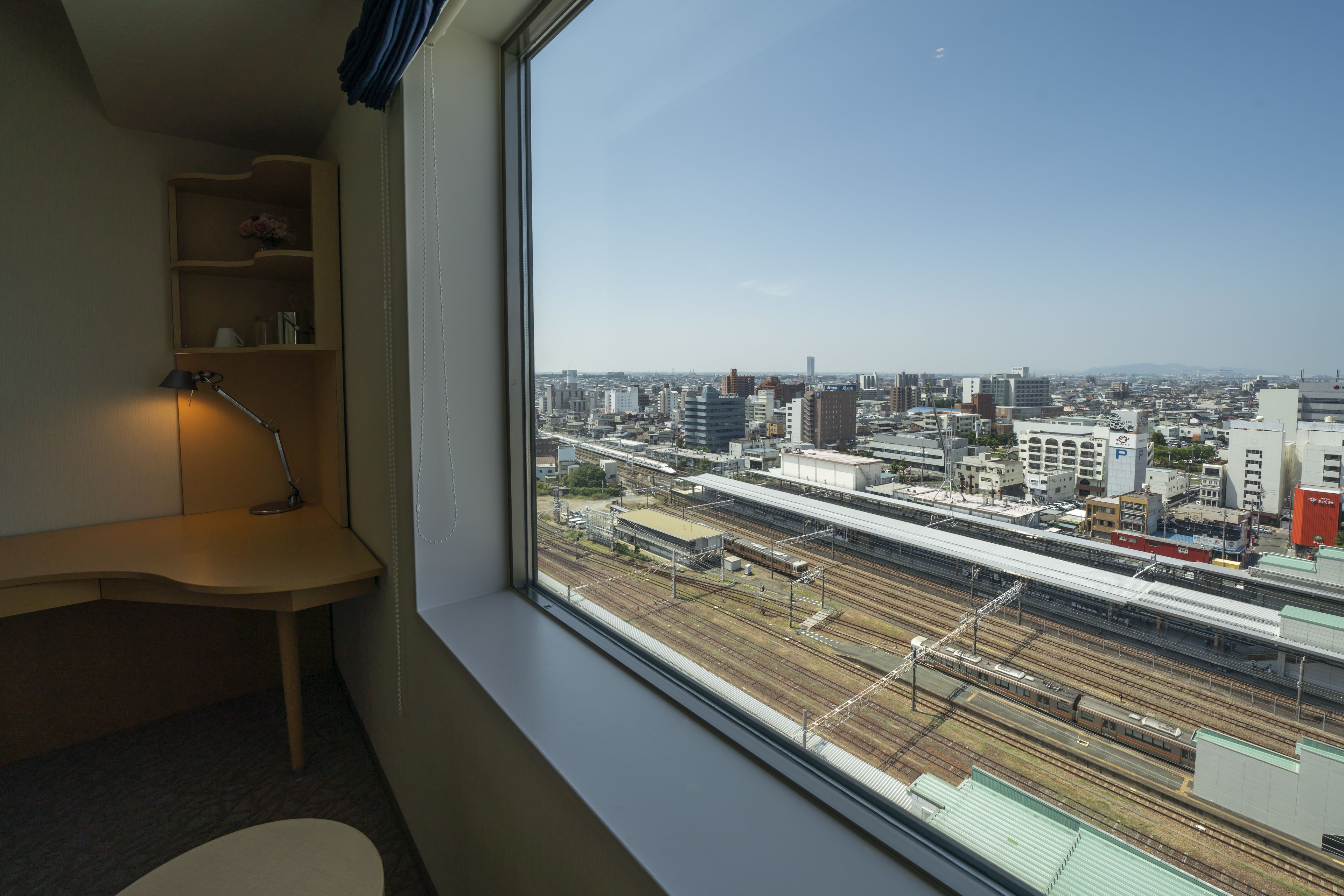 A room with a large window overlooking a cityscape and train tracks.