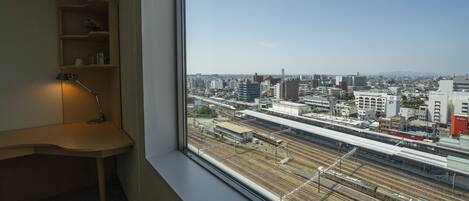 A room with a large window overlooking a cityscape and train tracks.