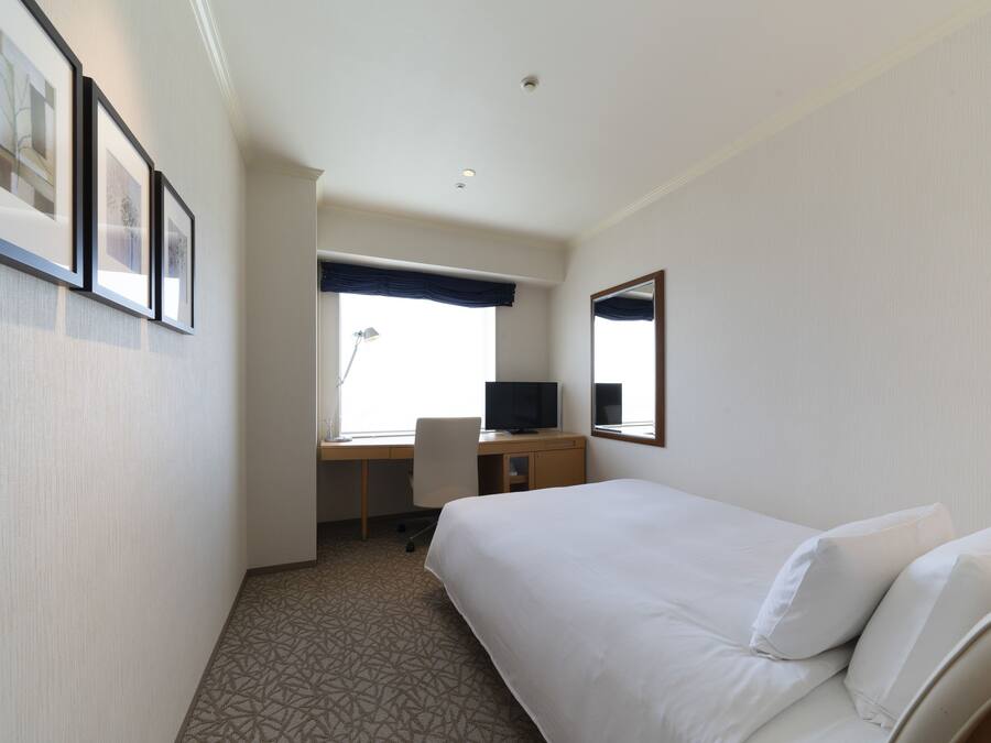 Une chambre d’hôtel avec un lit, un bureau et une chaise, une télévision et une fenêtre donnant sur un beau paysage.