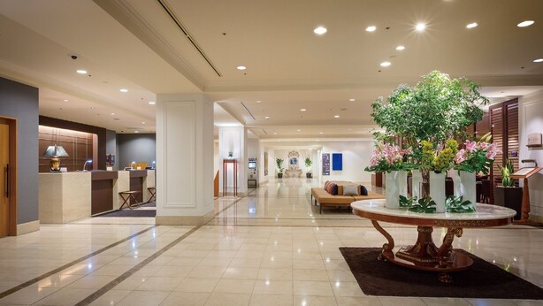 A spacious lobby with a reception desk, a seating area, and a decorative plant centerpiece. - Hotel Associa Toyohashi (Toyohashi)