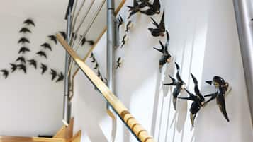 A staircase with a wooden handrail and wall-mounted bird sculptures.
