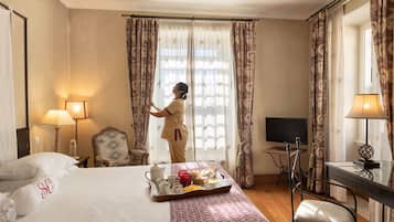 Une chambre d’hôtel avec un lit, un bureau, une chaise, un plateau de petit-déjeuner et des rideaux.