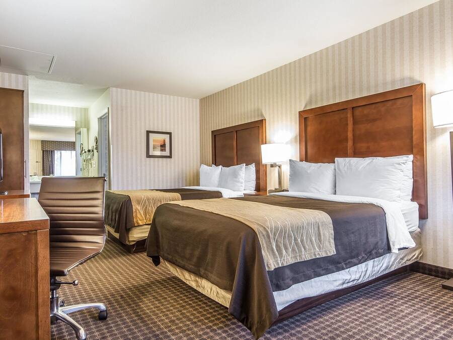 Quarto de hotel com duas camas, uma escrivaninha e uma cadeira.
