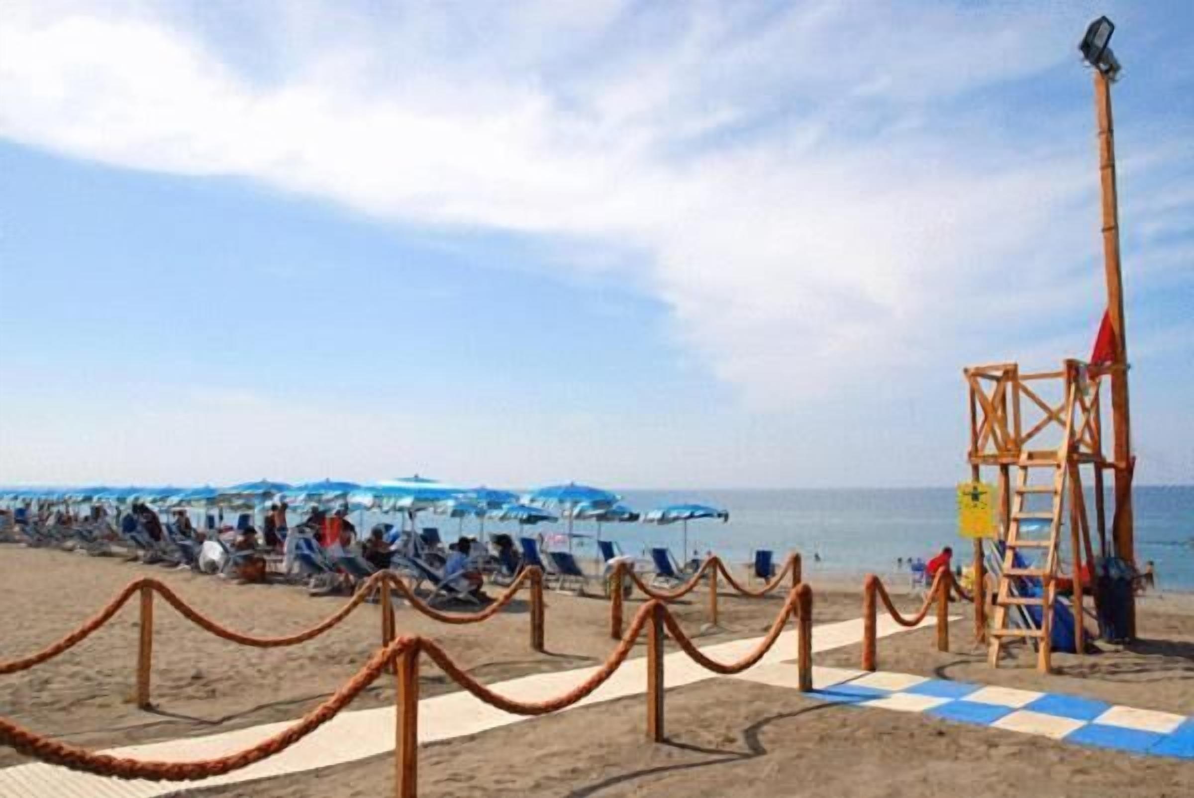 Una playa con una torre de salvavidas, tumbonas y sombrillas.