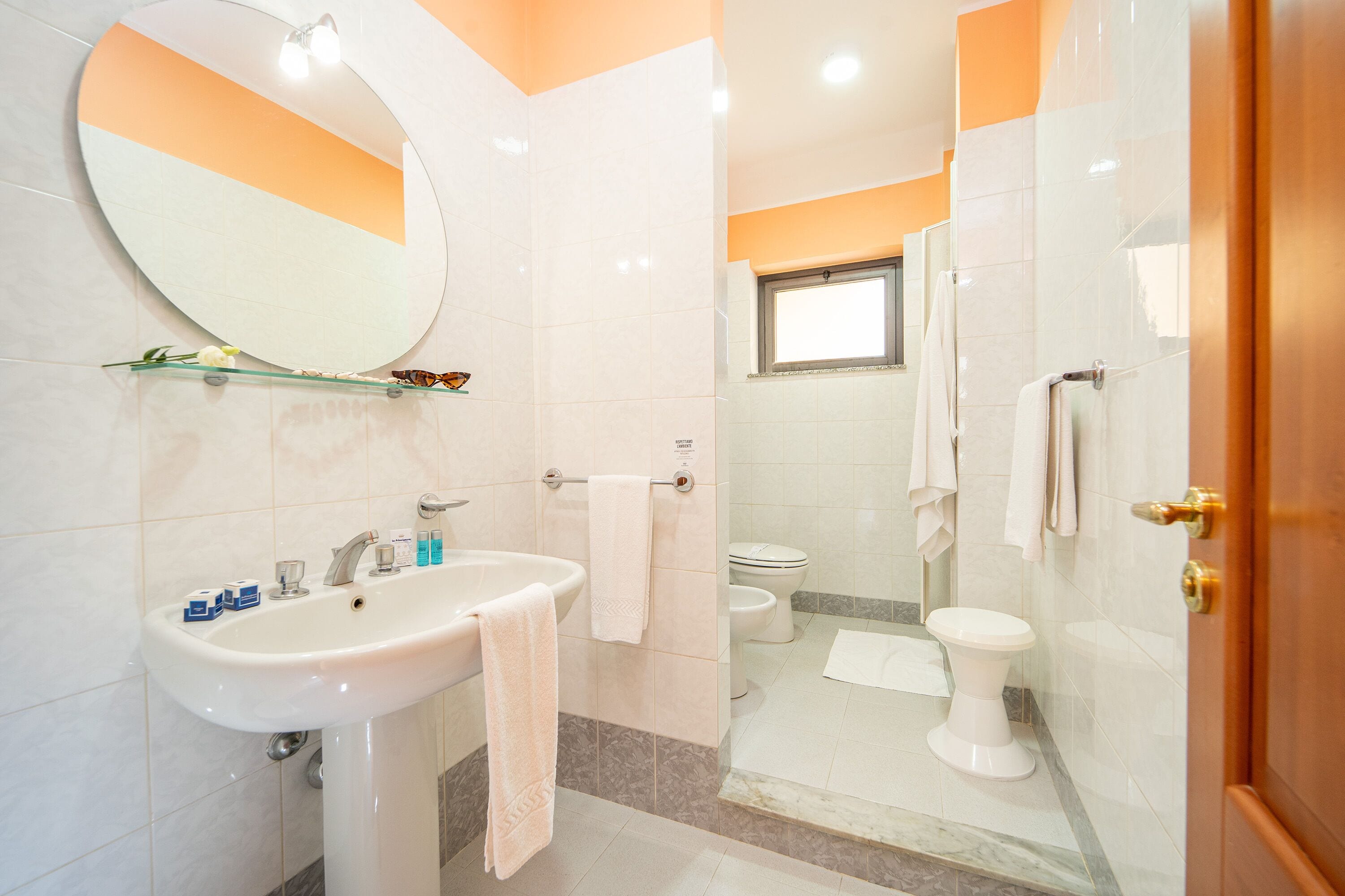 Un baño con lavamanos, espejo y dos inodoros.