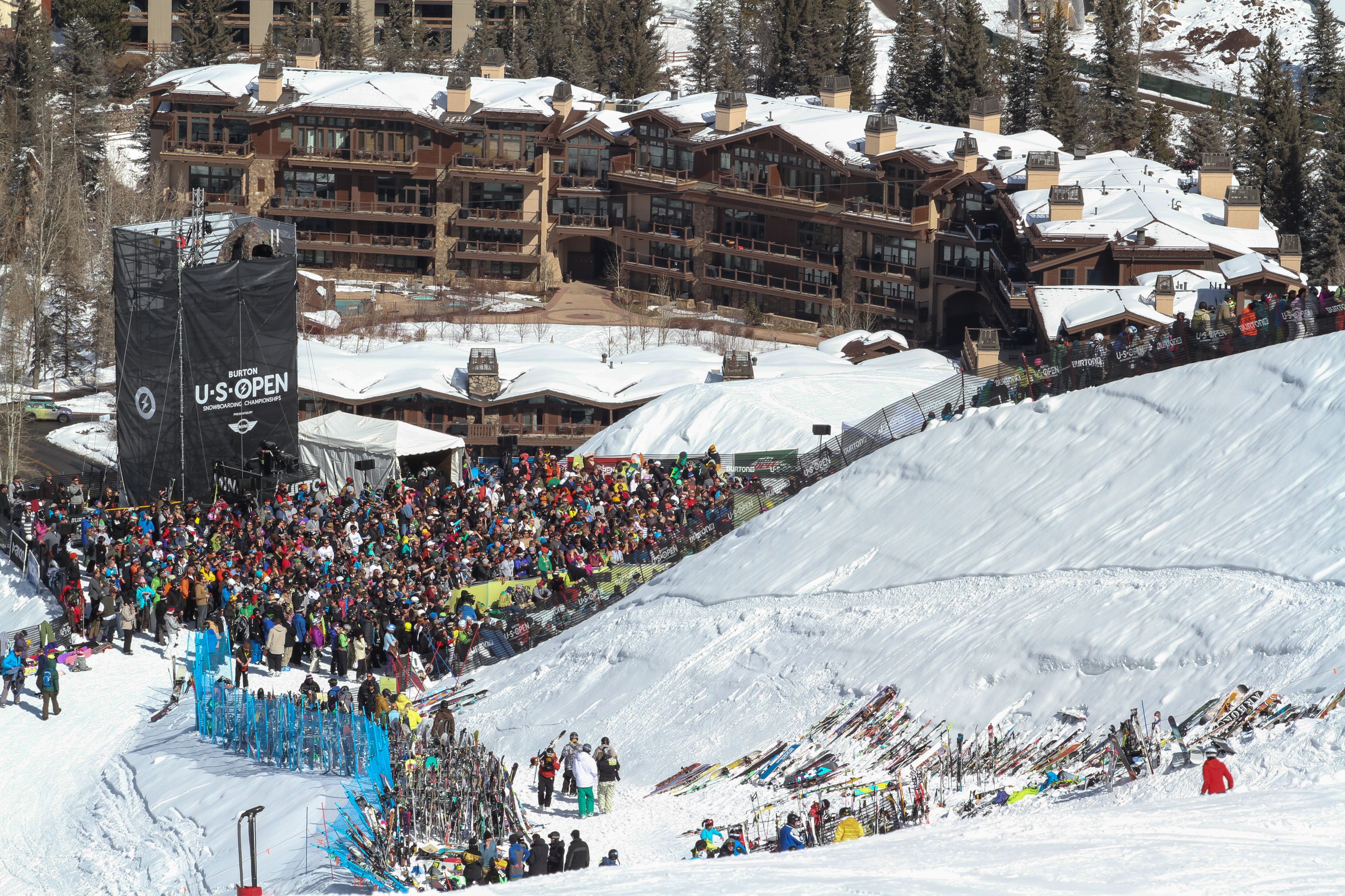 A ski resort with a large crowd of spectators and numerous ski equipment.