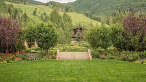 A mountain landscape with a wooden staircase leading to a building surrounded by lush greenery and trees.