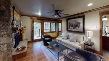 A cozy living room with a fireplace, a sofa, a coffee table, and a ceiling fan.