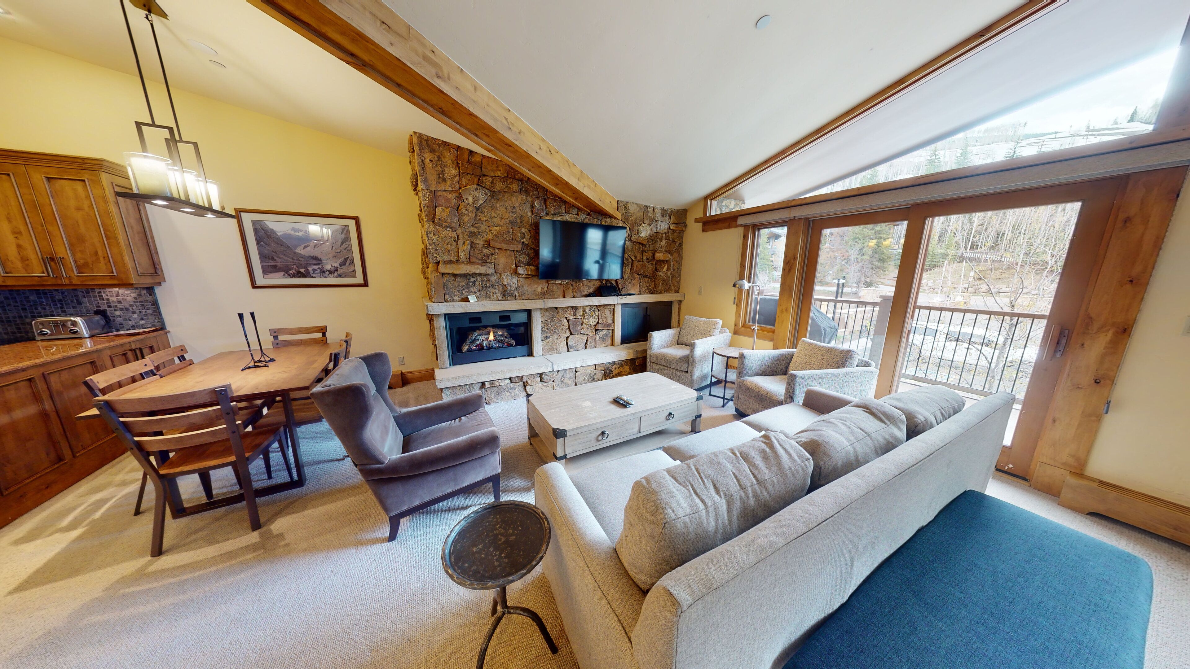 A cozy living area with a stone fireplace, a flat-screen TV, and a dining table with chairs.