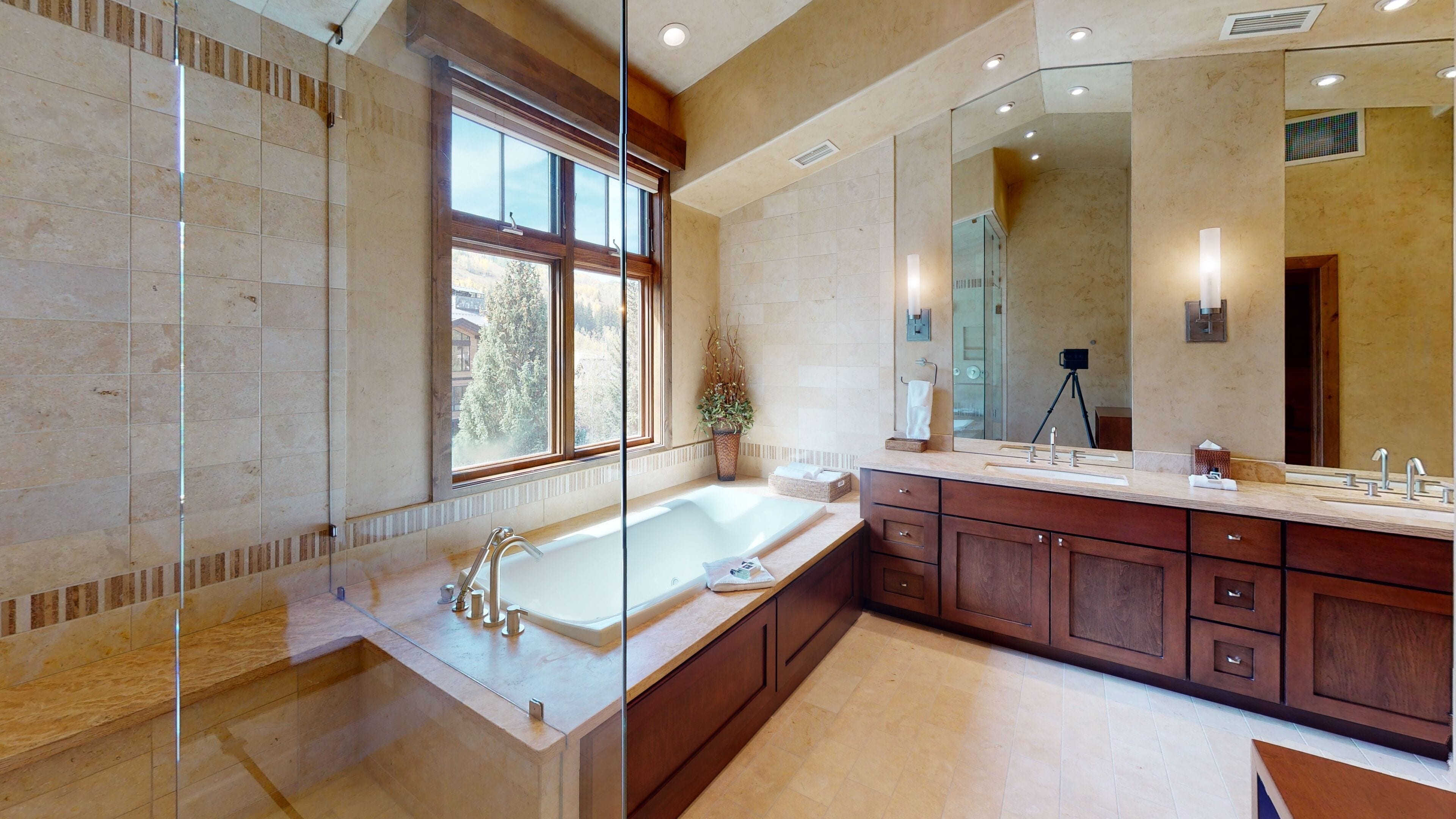A modern bathroom with a large bathtub, a walk-in shower, and a vanity with a large mirror.
