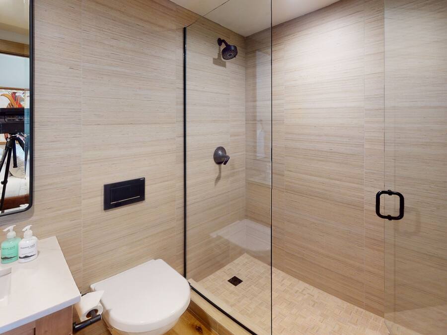 A modern bathroom with a glass shower enclosure, a white toilet, and a vanity with a mirror.