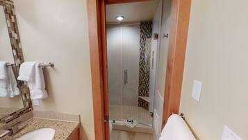 Un baño con lavamanos, espejo, toallero y una zona de ducha con pared de azulejos.