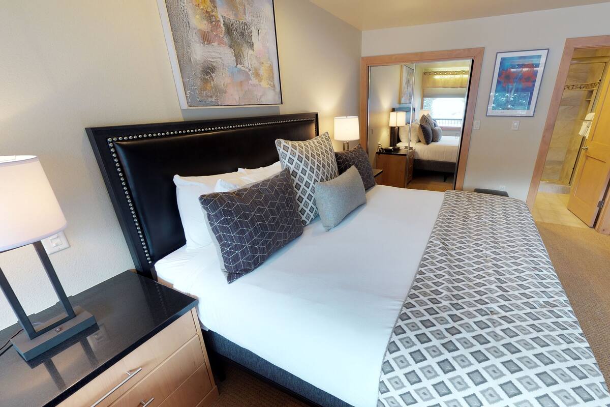 Una habitación de hotel con una cama grande, mesitas de noche, un escritorio y un armario.