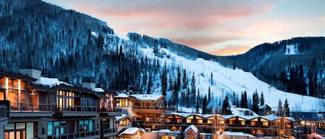 A multi-story hotel with a ski slope in the background.