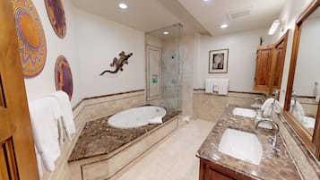 Un baño con una bañera grande, zona de ducha separada y tocador con lavabo.