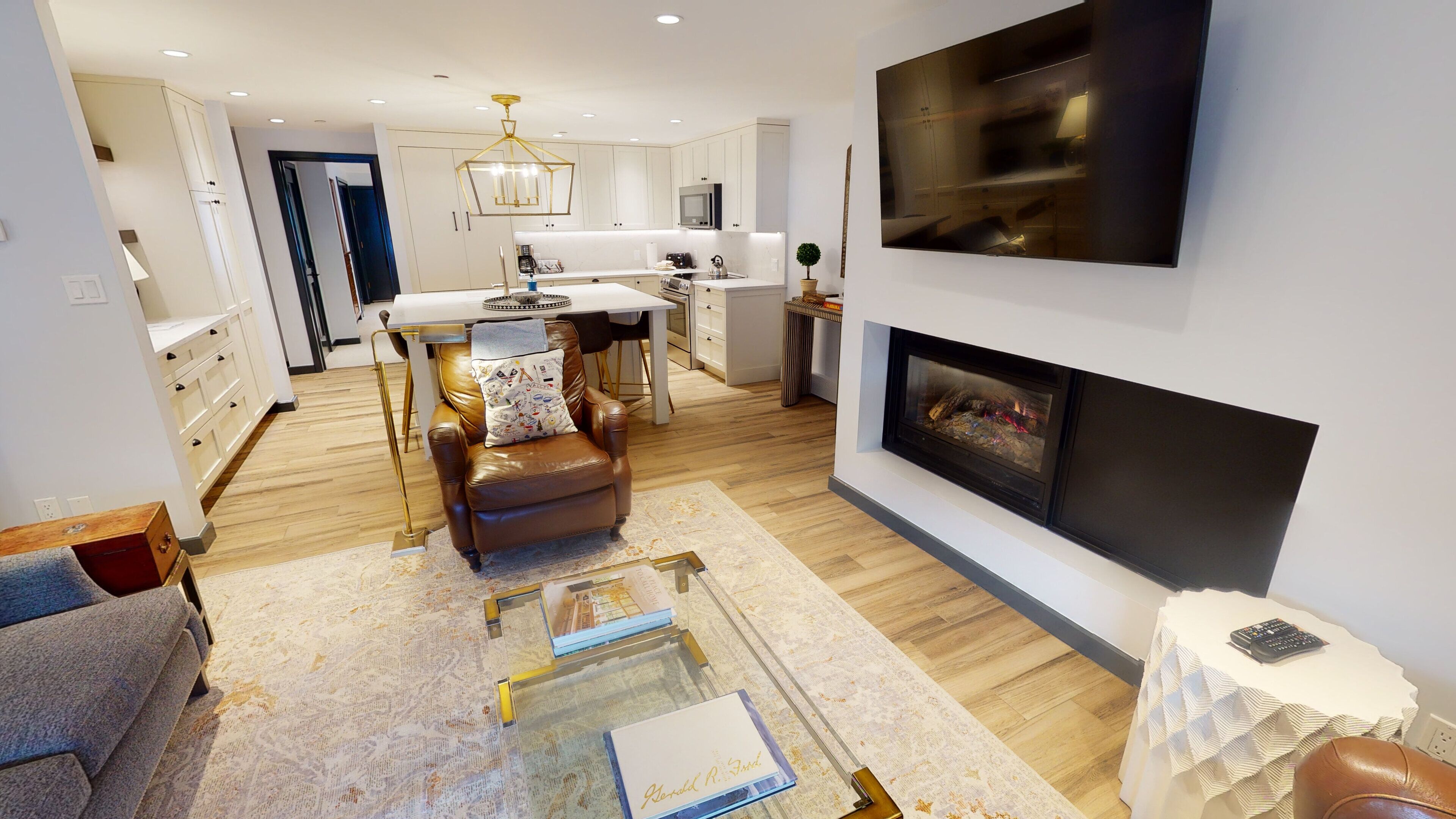 Una sala moderna con chimenea, sofá de cuero y un comedor con mesa y sillas blancas.