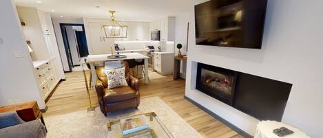 Una sala moderna con chimenea, sofá de cuero y un comedor con mesa y sillas blancas.