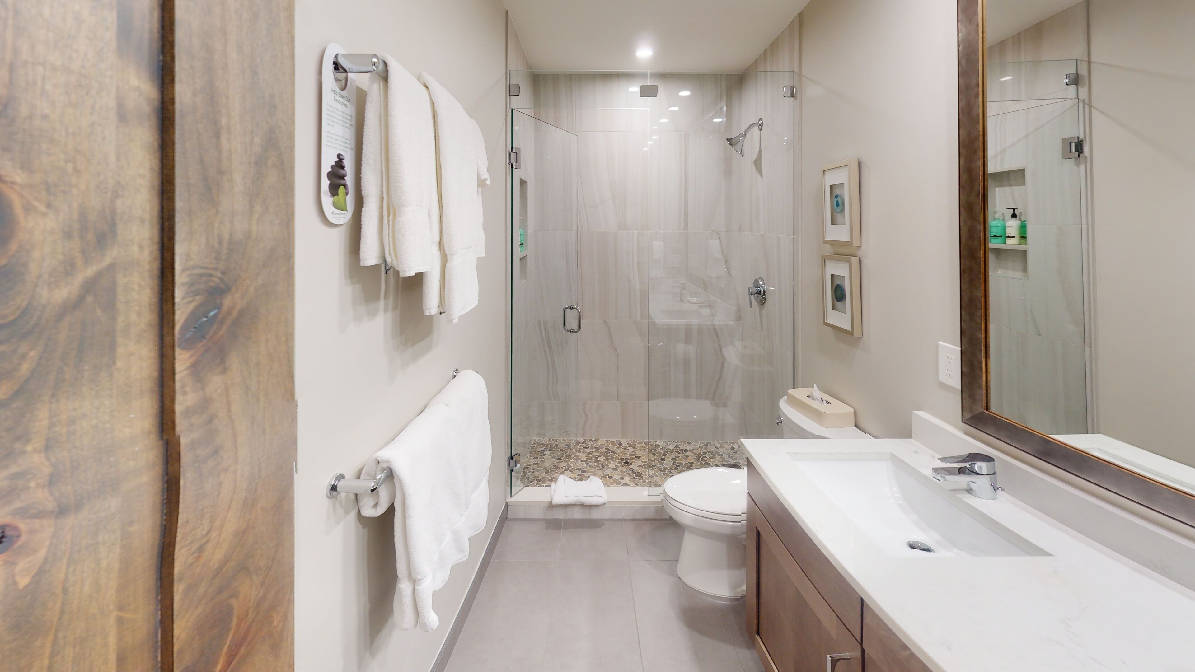 A modern bathroom with a glass-enclosed shower, a toilet, and a vanity with a mirror.