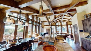 A spacious kitchen with a large island, wooden beams, and large windows.