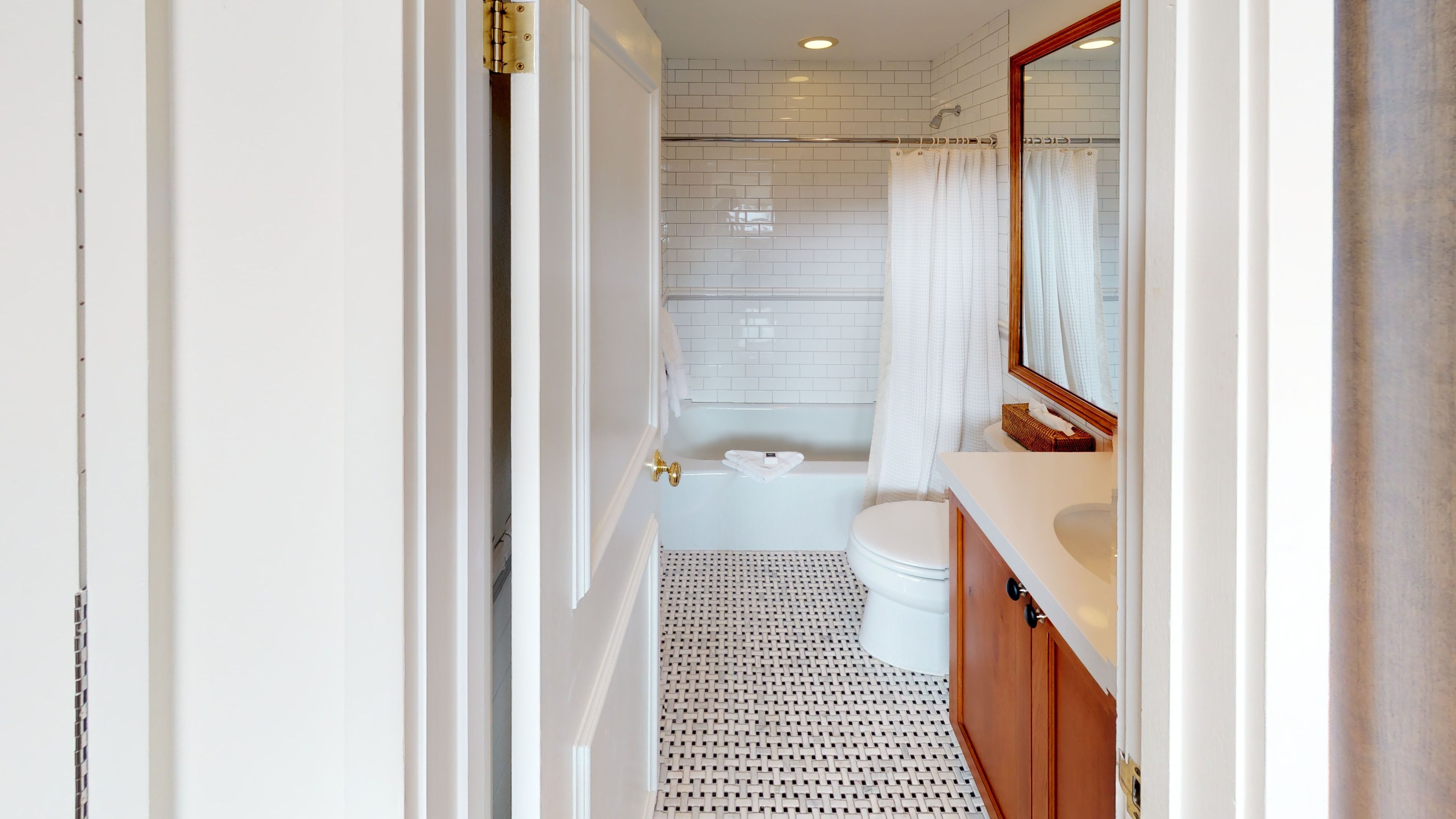 A modern bathroom with a white tiled shower, a white toilet, and a wooden vanity with a mirror.