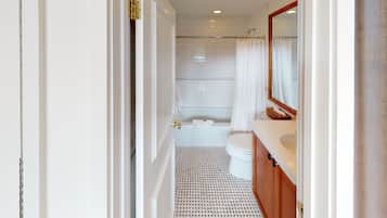 A modern bathroom with a white tiled shower, a white toilet, and a wooden vanity with a mirror.